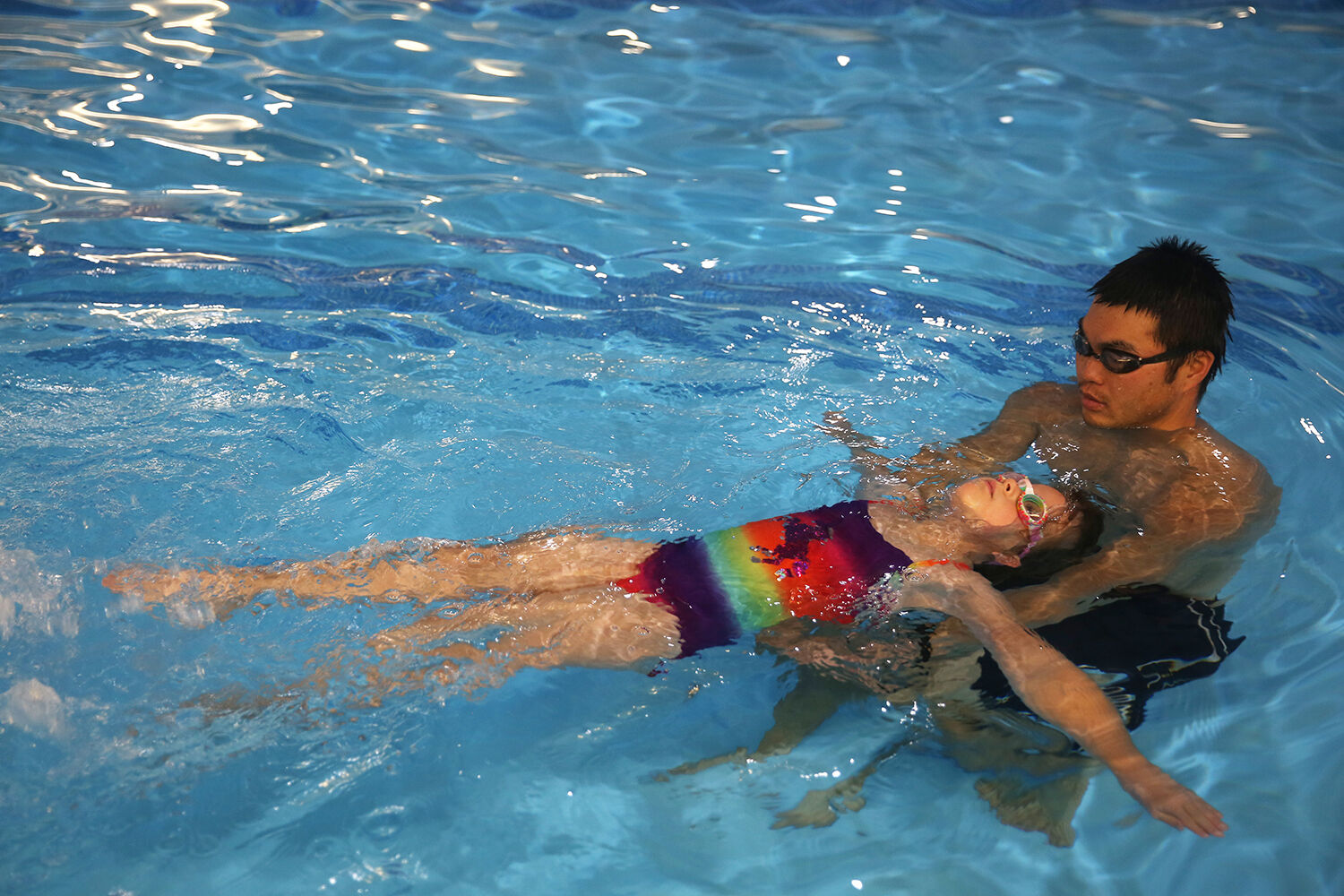 Kennedy McCoy, 6, practices floating and kicking with Caleb Cohoon